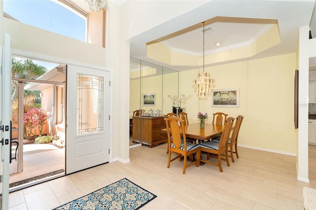 dining space featuring baseboards, ornamental molding, a raised ceiling, and an inviting chandelier