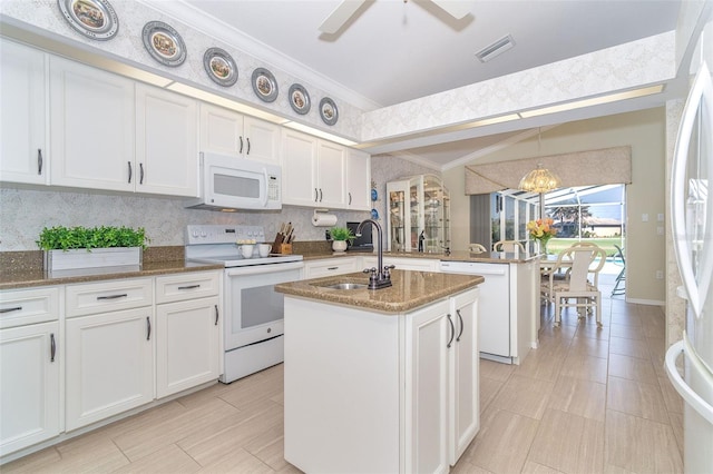 kitchen with white appliances, white cabinets, a kitchen island with sink, crown molding, and a sink