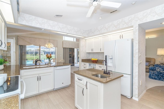 kitchen with white appliances, visible vents, dark stone counters, white cabinetry, and a sink