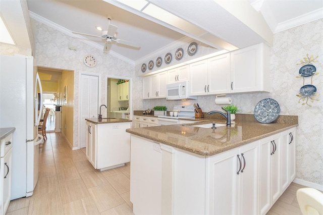 kitchen with lofted ceiling, white appliances, a sink, ornamental molding, and wallpapered walls