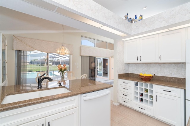 kitchen featuring white cabinetry, vaulted ceiling, a sink, dark stone countertops, and dishwasher