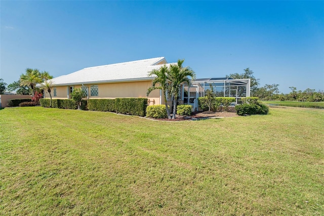 view of front of home featuring glass enclosure, a front lawn, and stucco siding