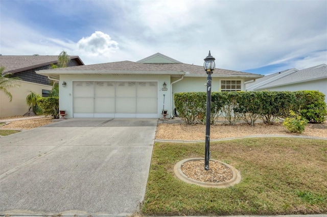 ranch-style house featuring a garage, concrete driveway, stucco siding, roof with shingles, and a front yard