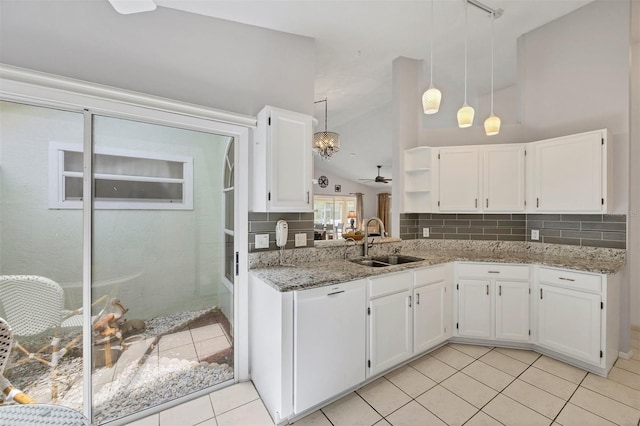 kitchen featuring lofted ceiling, light stone counters, a sink, and decorative backsplash