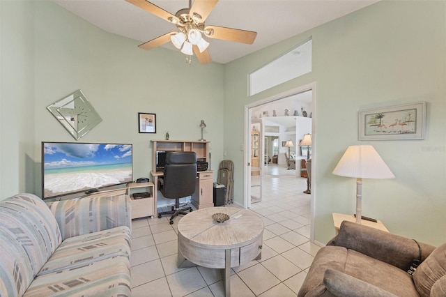 living room with light tile patterned floors, a high ceiling, a ceiling fan, and baseboards