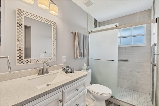 bathroom featuring toilet, a stall shower, vanity, and visible vents