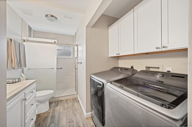 washroom featuring laundry area, baseboards, washer and clothes dryer, and light wood finished floors