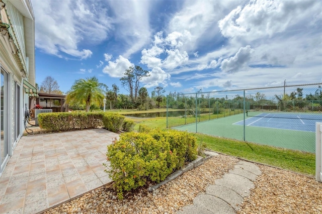 view of tennis court featuring a patio and fence