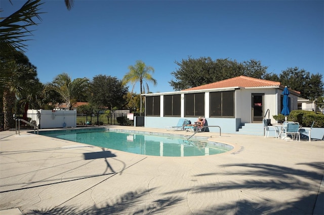 pool with a patio area, fence, and a sunroom