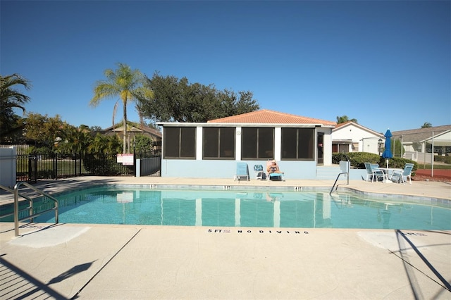 pool featuring a patio area, fence, and a sunroom