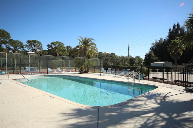 community pool with a patio area and fence