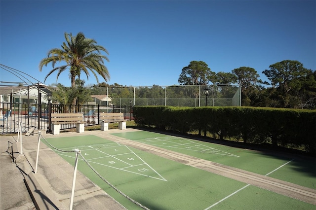 view of community with shuffleboard and fence