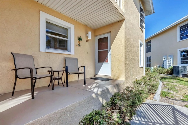 doorway to property featuring cooling unit, a patio area, and stucco siding