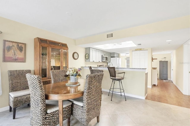 dining space featuring light tile patterned floors, visible vents, baseboards, and a ceiling fan