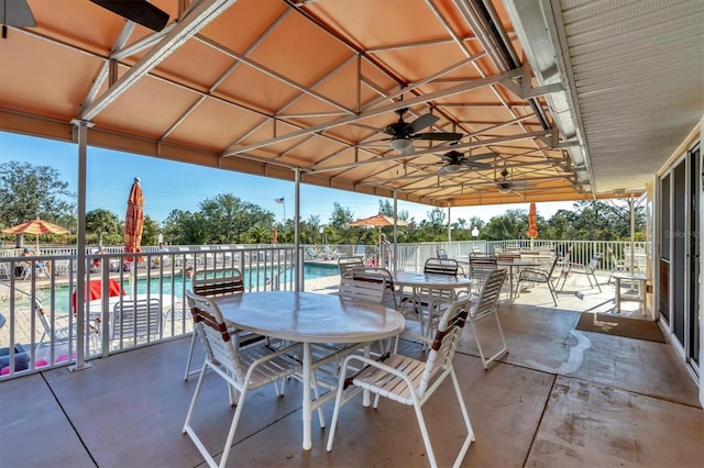 view of patio with outdoor dining area, a community pool, and ceiling fan