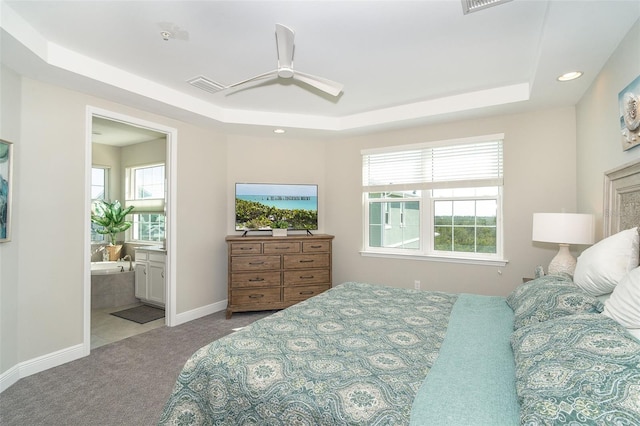 bedroom with baseboards, visible vents, connected bathroom, a tray ceiling, and carpet flooring