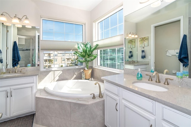 bathroom featuring a stall shower, two vanities, a sink, and a bath