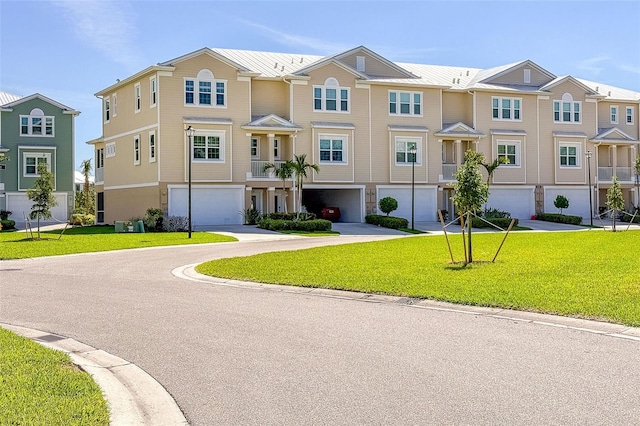 multi unit property featuring a garage, driveway, a residential view, and a front yard