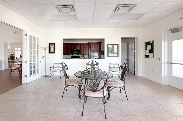 dining space featuring light tile patterned flooring, visible vents, a drop ceiling, and french doors