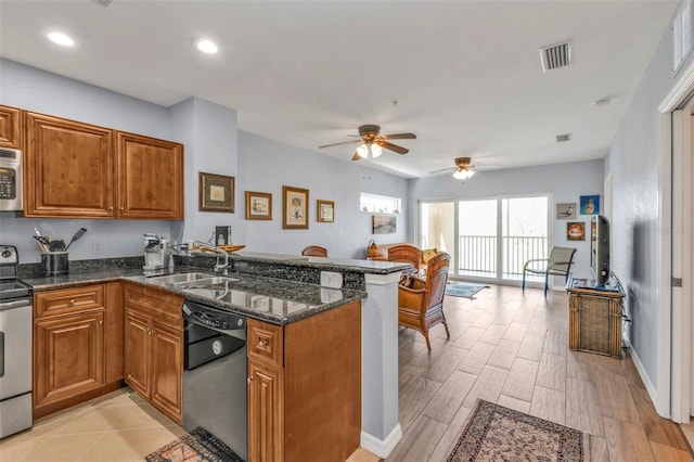 kitchen featuring visible vents, appliances with stainless steel finishes, brown cabinetry, a sink, and a peninsula