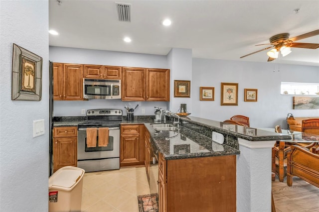 kitchen featuring brown cabinets, visible vents, appliances with stainless steel finishes, dark stone countertops, and a peninsula