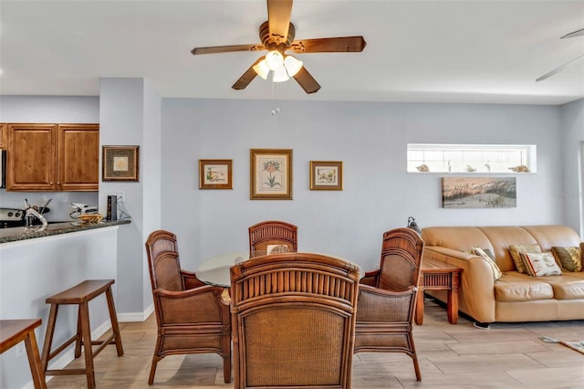 dining room featuring ceiling fan, light wood-type flooring, and baseboards