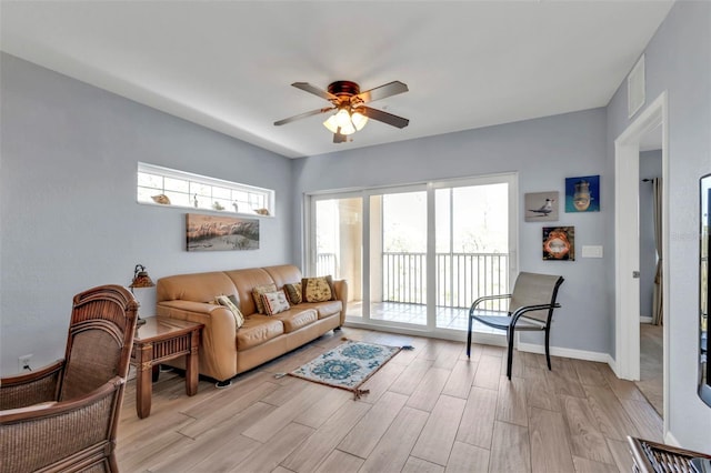 living room with light wood-type flooring, baseboards, and a ceiling fan