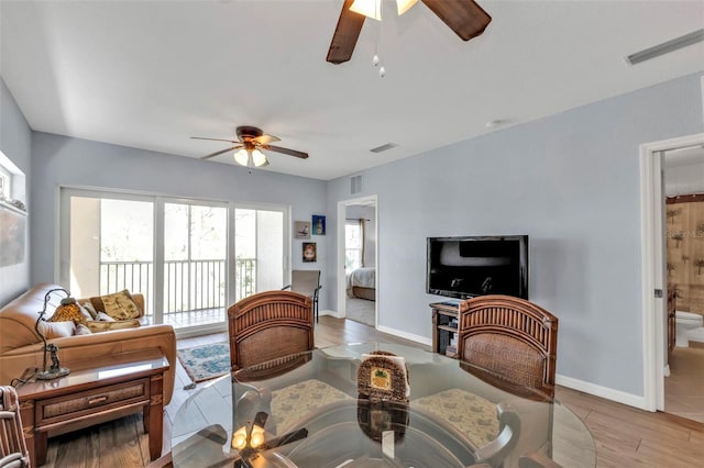 living room with a ceiling fan, visible vents, and baseboards