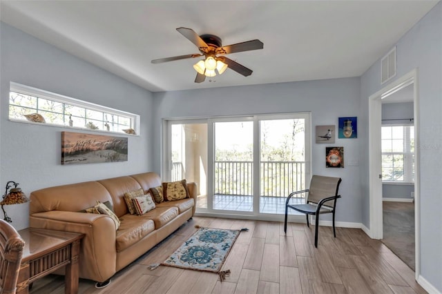 living area with baseboards, visible vents, ceiling fan, and light wood finished floors