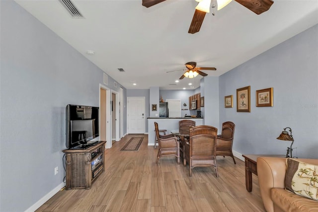 dining area with ceiling fan, light wood-style flooring, visible vents, and baseboards