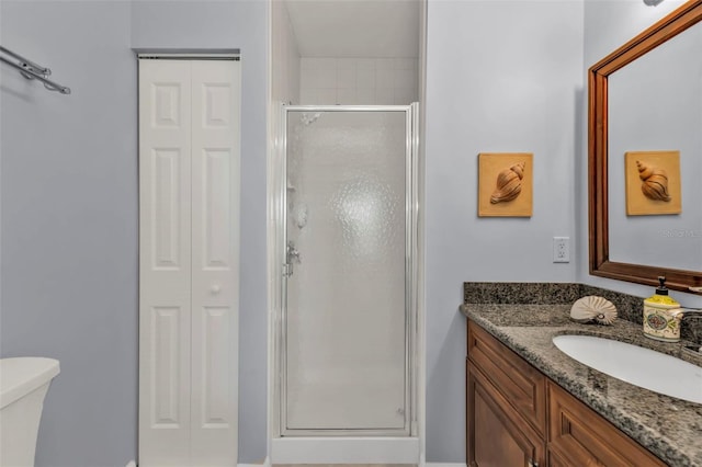 full bathroom with a closet, toilet, a shower stall, and vanity