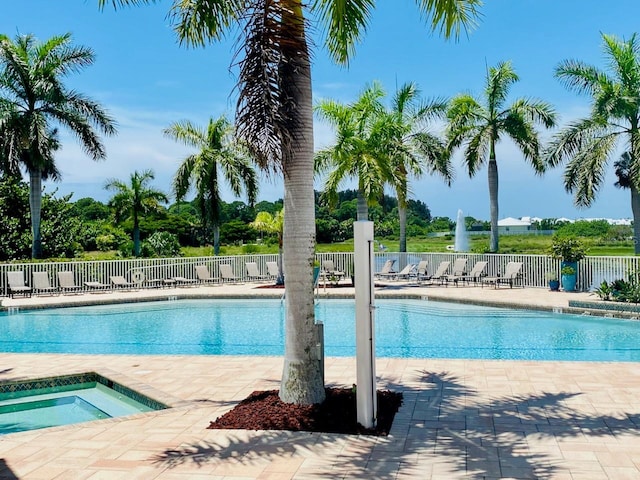 pool featuring fence, a hot tub, and a patio