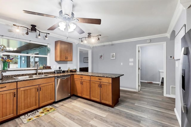 kitchen with stainless steel appliances, brown cabinets, a sink, and a peninsula