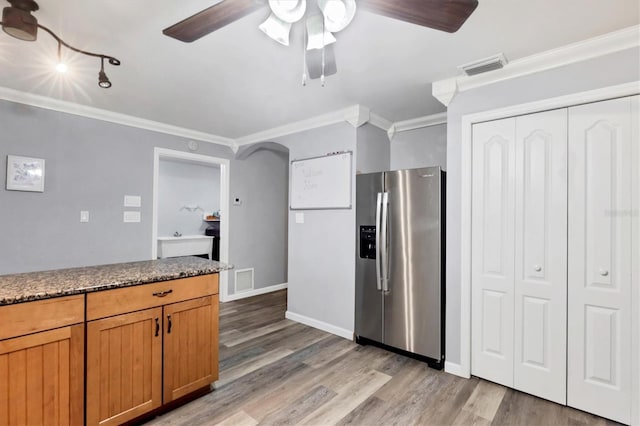 kitchen with ornamental molding, light wood-type flooring, stainless steel fridge, and visible vents