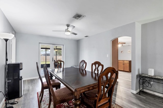 dining room with arched walkways, ceiling fan, light wood-style flooring, visible vents, and baseboards