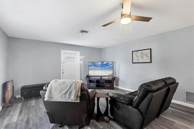 living room with baseboards, visible vents, and wood finished floors