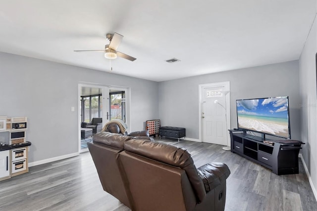 living room with ceiling fan, wood finished floors, visible vents, and baseboards