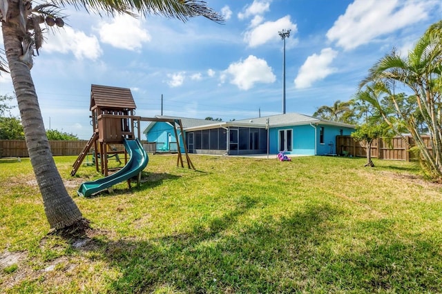 exterior space with a sunroom, a playground, a yard, and a fenced backyard