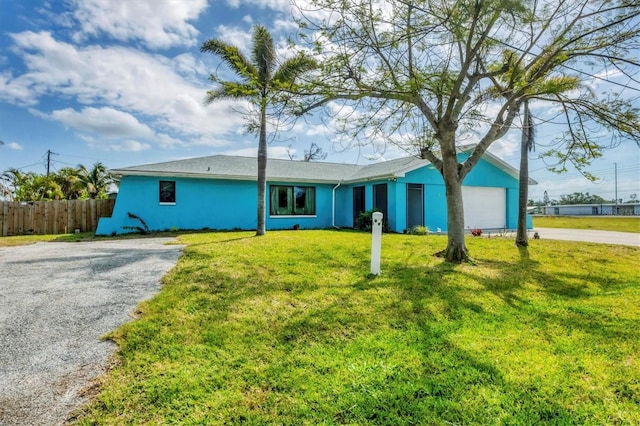 single story home with driveway, an attached garage, fence, a front yard, and stucco siding