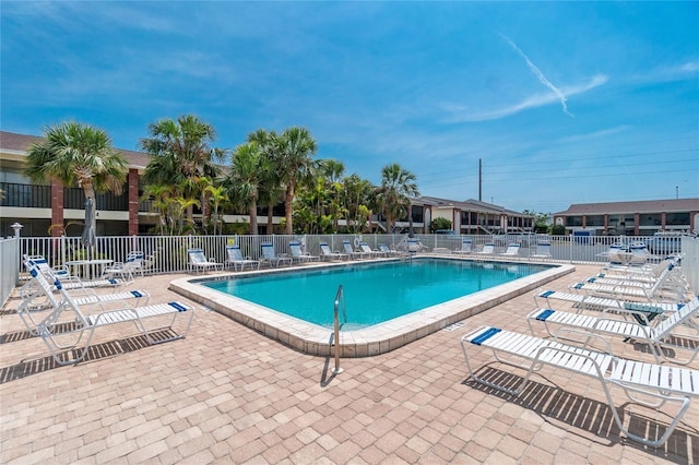 community pool with a patio area and fence