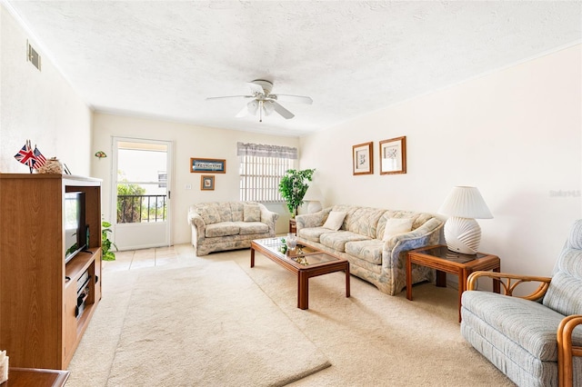 living area featuring light carpet, a ceiling fan, visible vents, and a textured ceiling