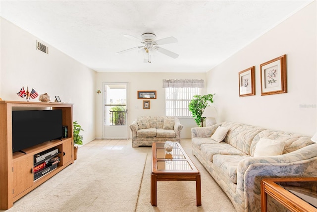 living room with light carpet, visible vents, and a ceiling fan