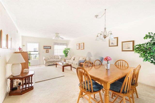 dining area featuring ceiling fan with notable chandelier and light colored carpet