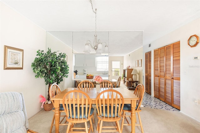 dining room with a chandelier, light colored carpet, and ornamental molding