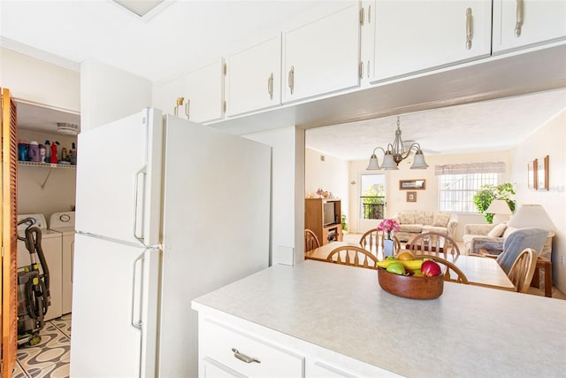 kitchen featuring white cabinets, washer and clothes dryer, open floor plan, freestanding refrigerator, and an inviting chandelier