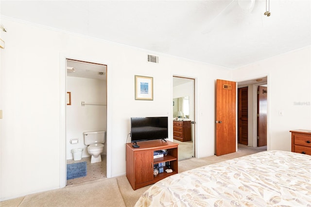 bedroom with ornamental molding, light colored carpet, visible vents, and ensuite bath