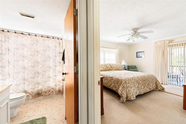 bedroom with a ceiling fan, access to outside, visible vents, and a textured ceiling