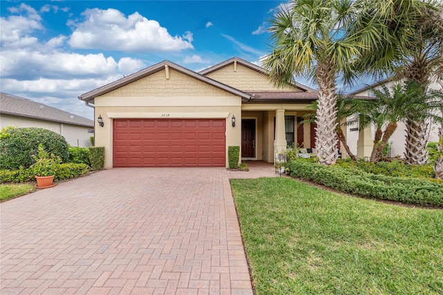 single story home featuring an attached garage, a front lawn, decorative driveway, and stucco siding