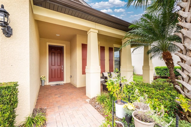 doorway to property with a porch and stucco siding