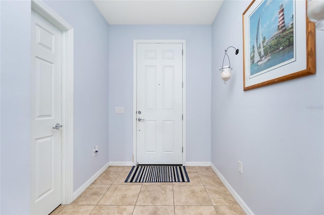 doorway to outside featuring baseboards and light tile patterned flooring